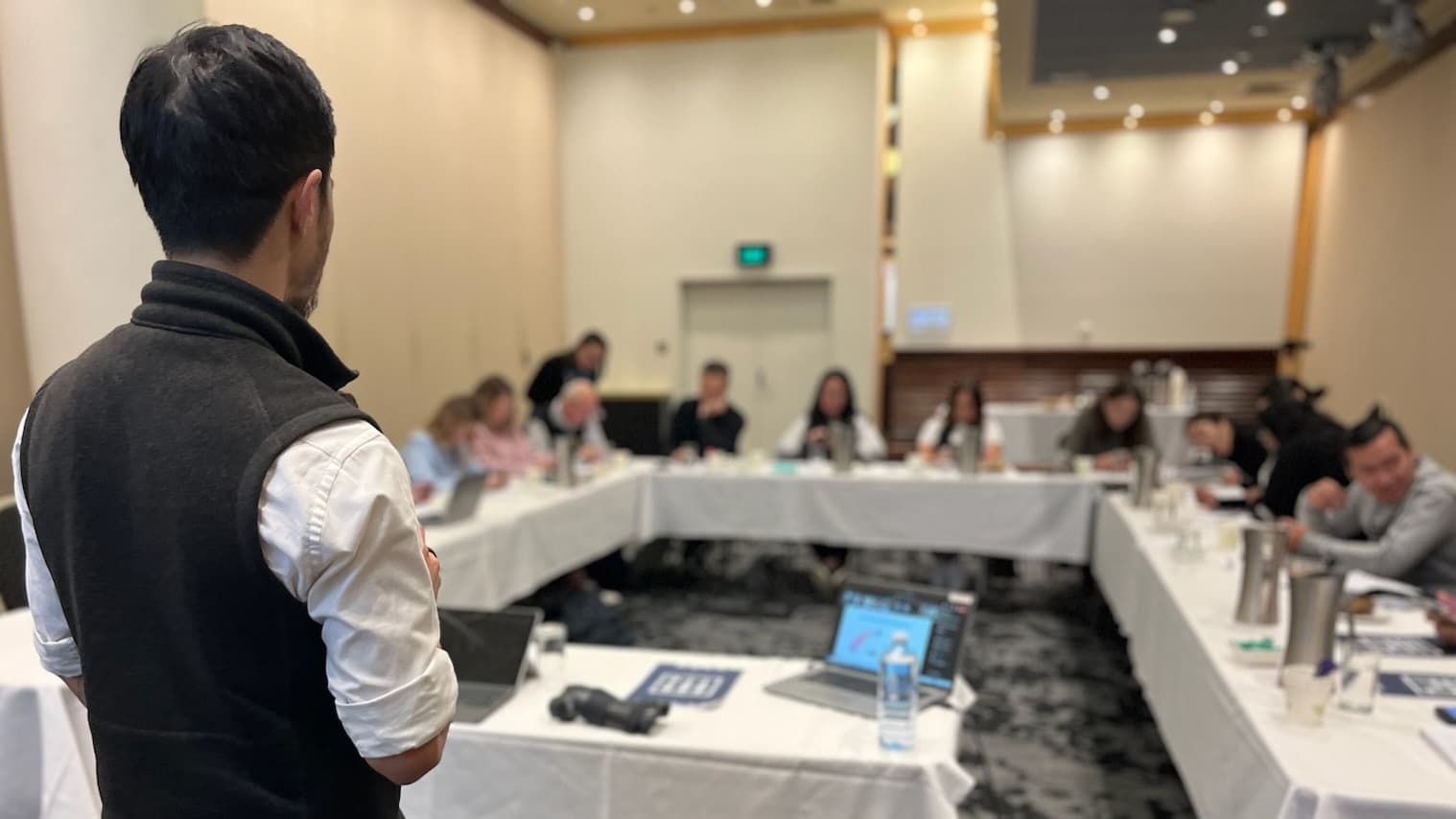 Jeremy Khoh facilitating a workshop for a group seated around tables